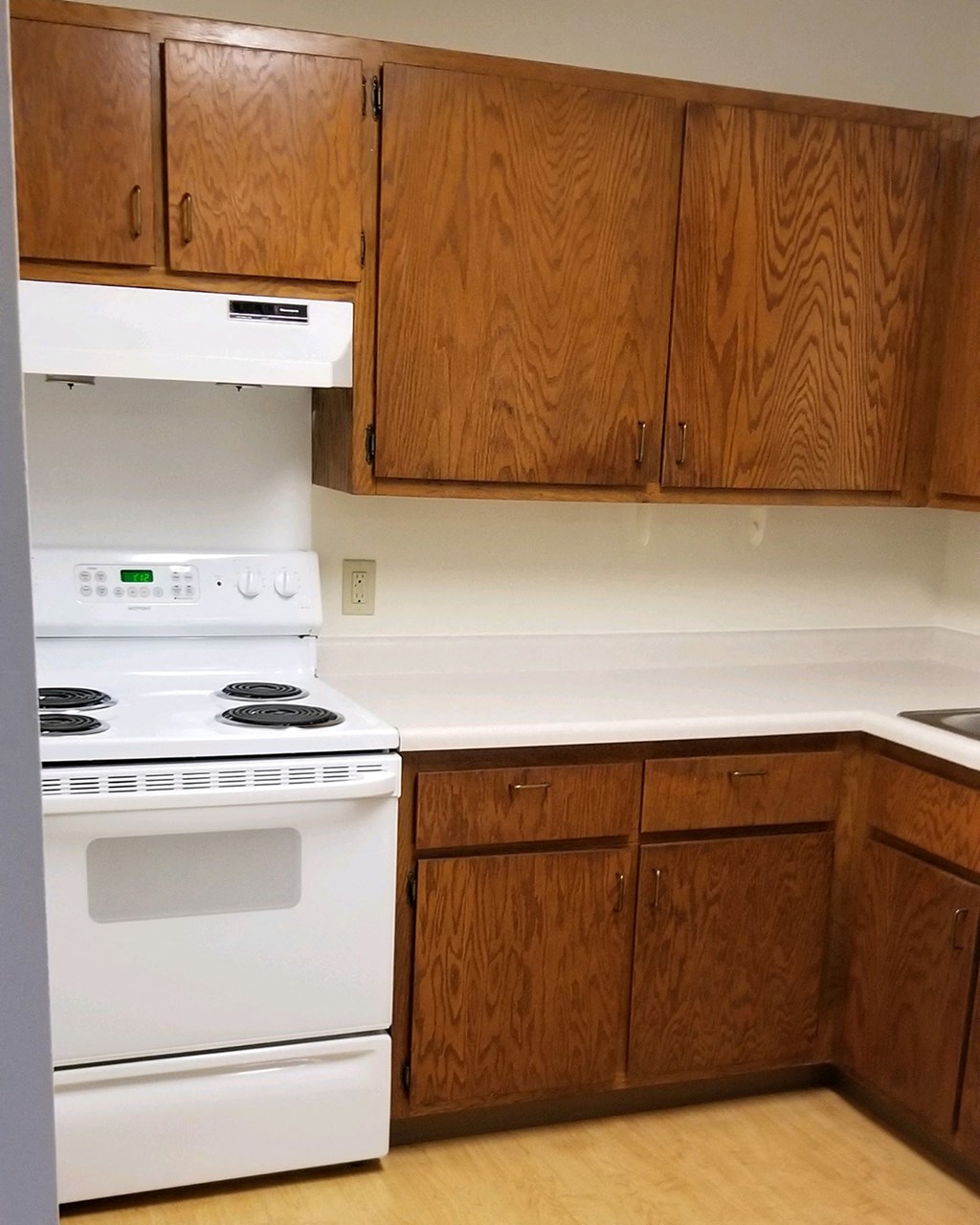 an empty kitchen with white appliances and wooden cabinets