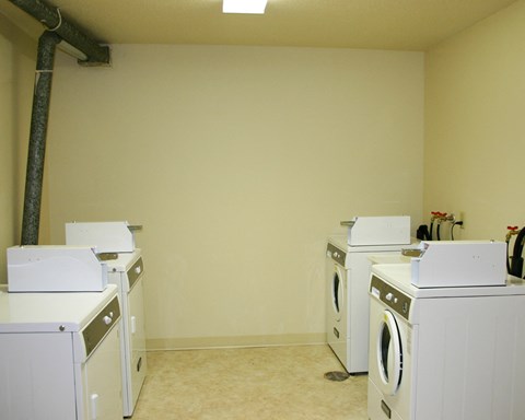 an empty laundry room with four washing machines
