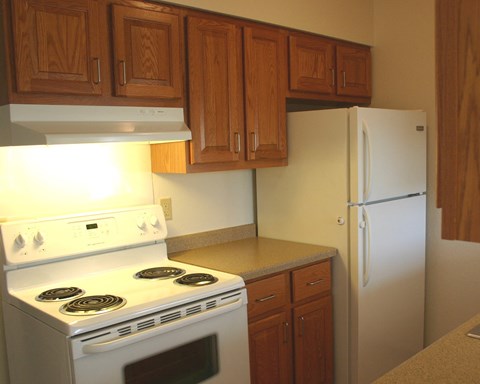 a kitchen with white appliances and wooden cabinets and a refrigerator