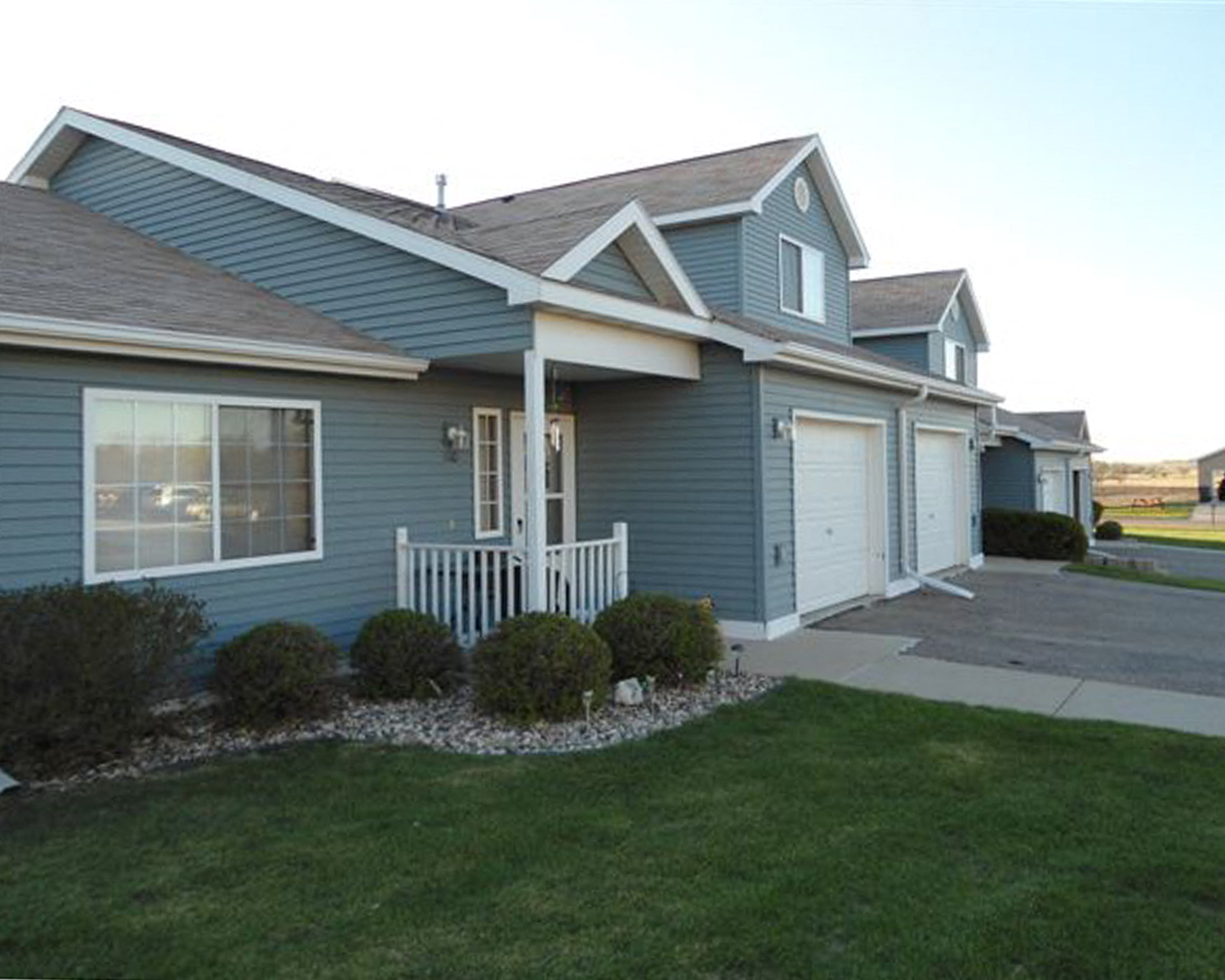 a blue house with a porch and a lawn