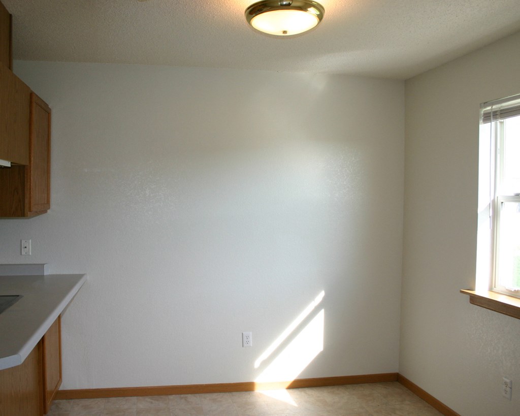 an empty kitchen with white walls and a light on the ceiling