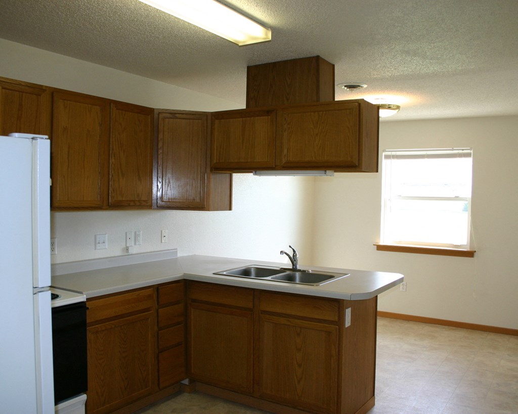 an empty kitchen with wooden cabinets and a sink