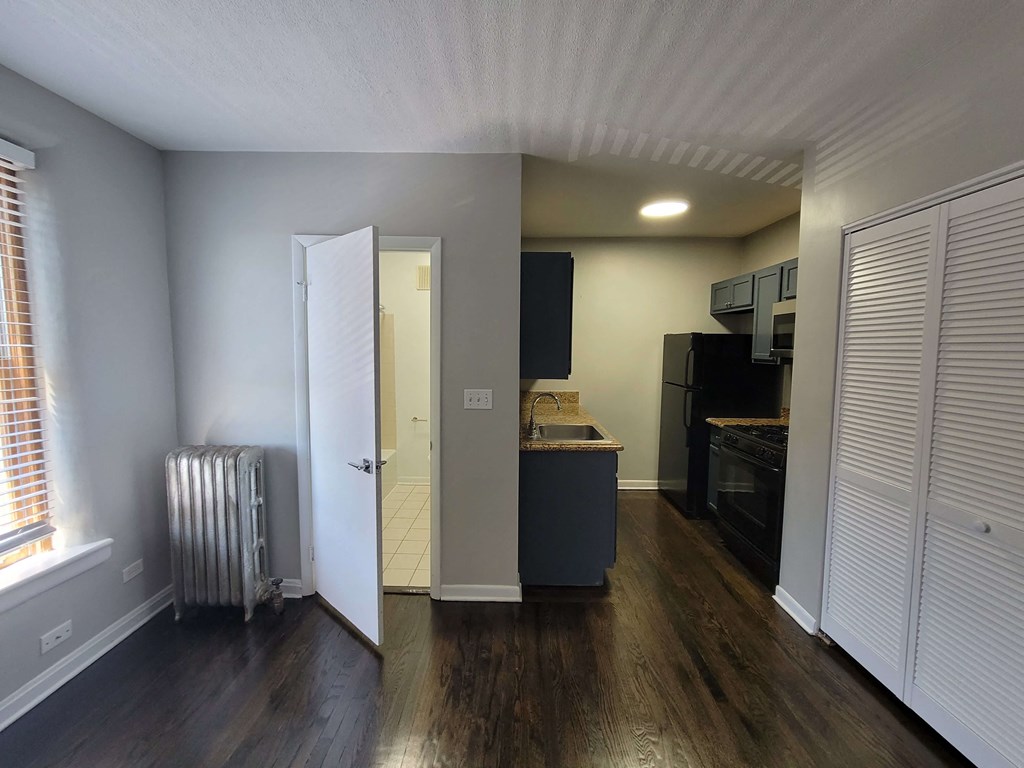 a living room with wood floors and a kitchen