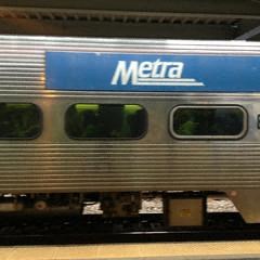 a silver train with a blue metro sign on it