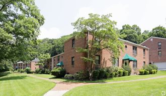a brick apartment building with green grass and trees