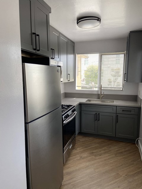 a kitchen with gray cabinets and a stainless steel refrigerator