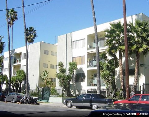 a building with palm trees and cars parked in front of it