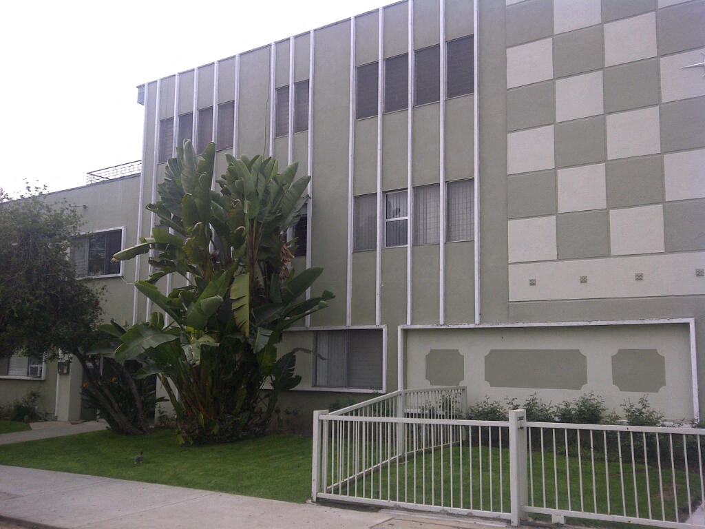 an apartment building with a fence and a garden in front of it