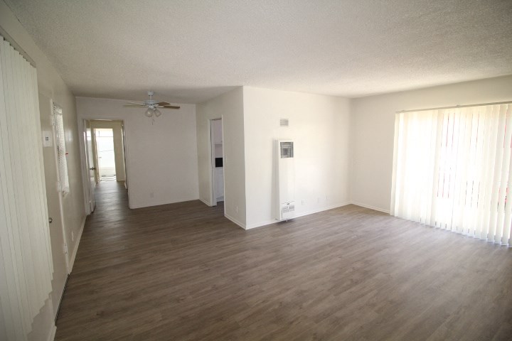 an empty living room with wood floors and a ceiling fan