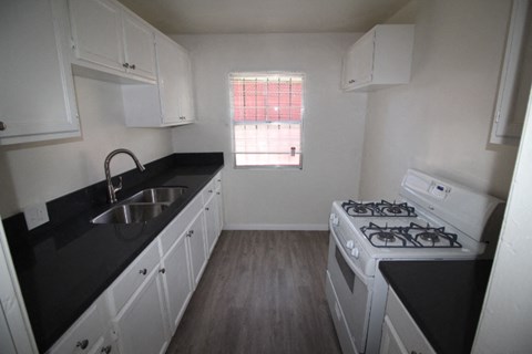 an empty kitchen with white appliances and black counter tops