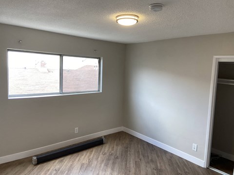 an empty room with a window and wooden floors