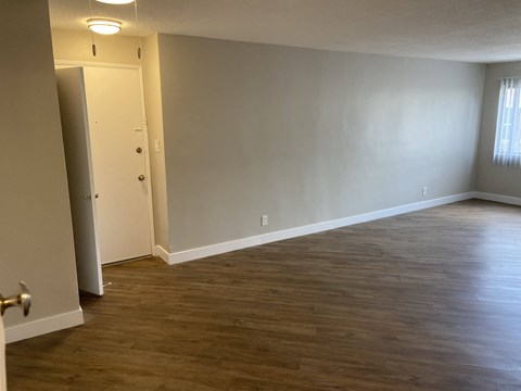 an empty living room with wood floors and white walls