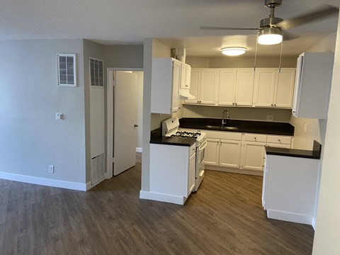 an empty kitchen with white cabinets and a black counter top