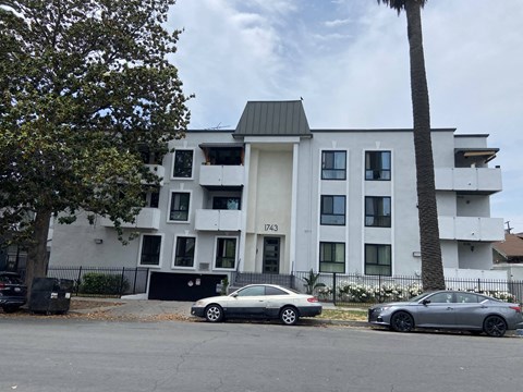 a white apartment building with two cars parked in front of it