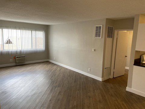 an empty living room with wood floors and a window