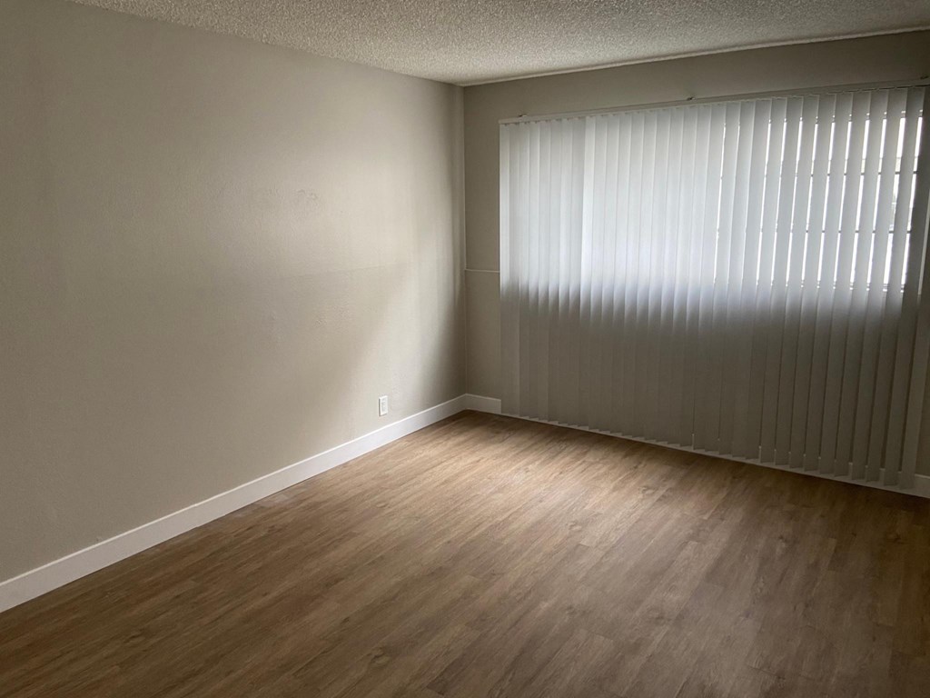 an empty living room with wood floors and a large window