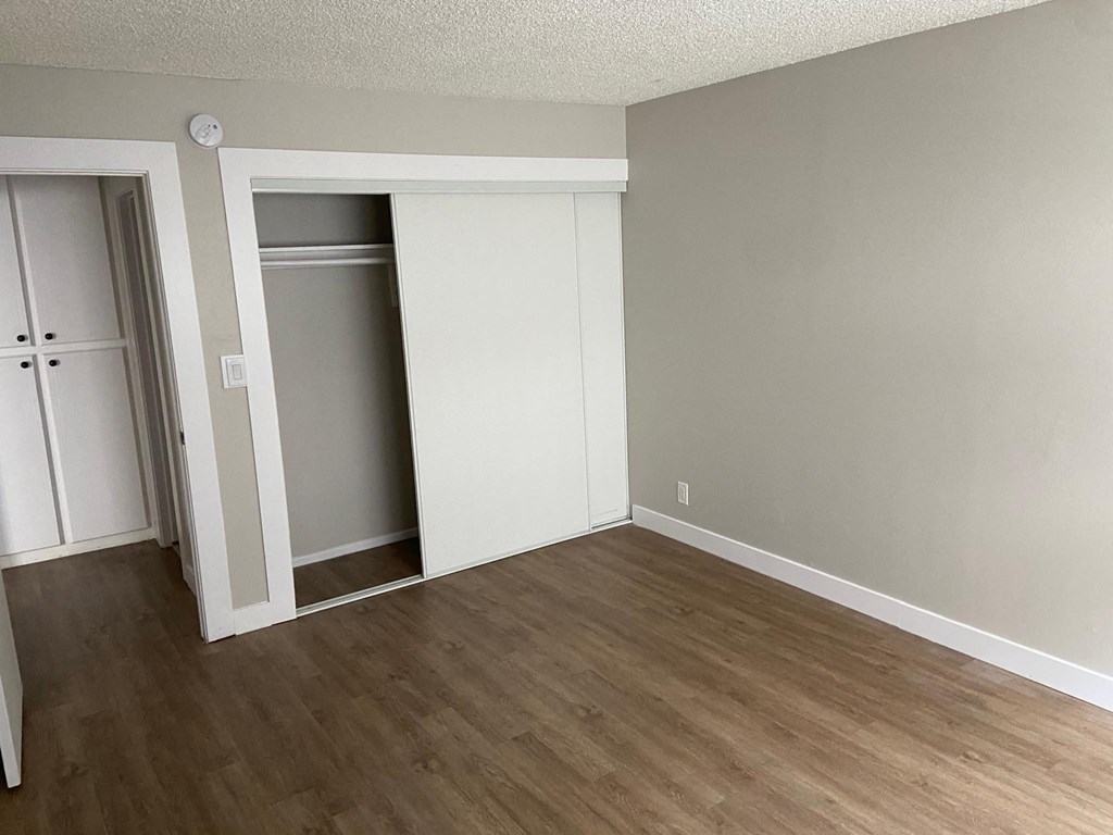 an empty living room with wood floors and a closet