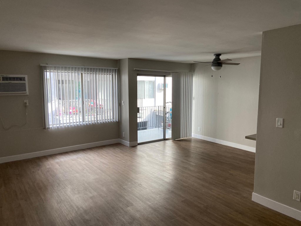 an empty living room with wood floors and a sliding glass door