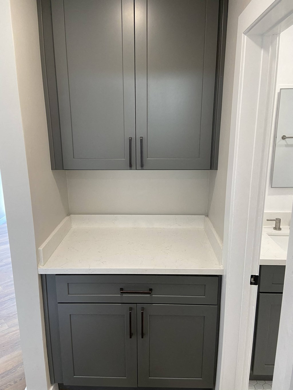 a small kitchen with gray cabinets and white countertops and a sink