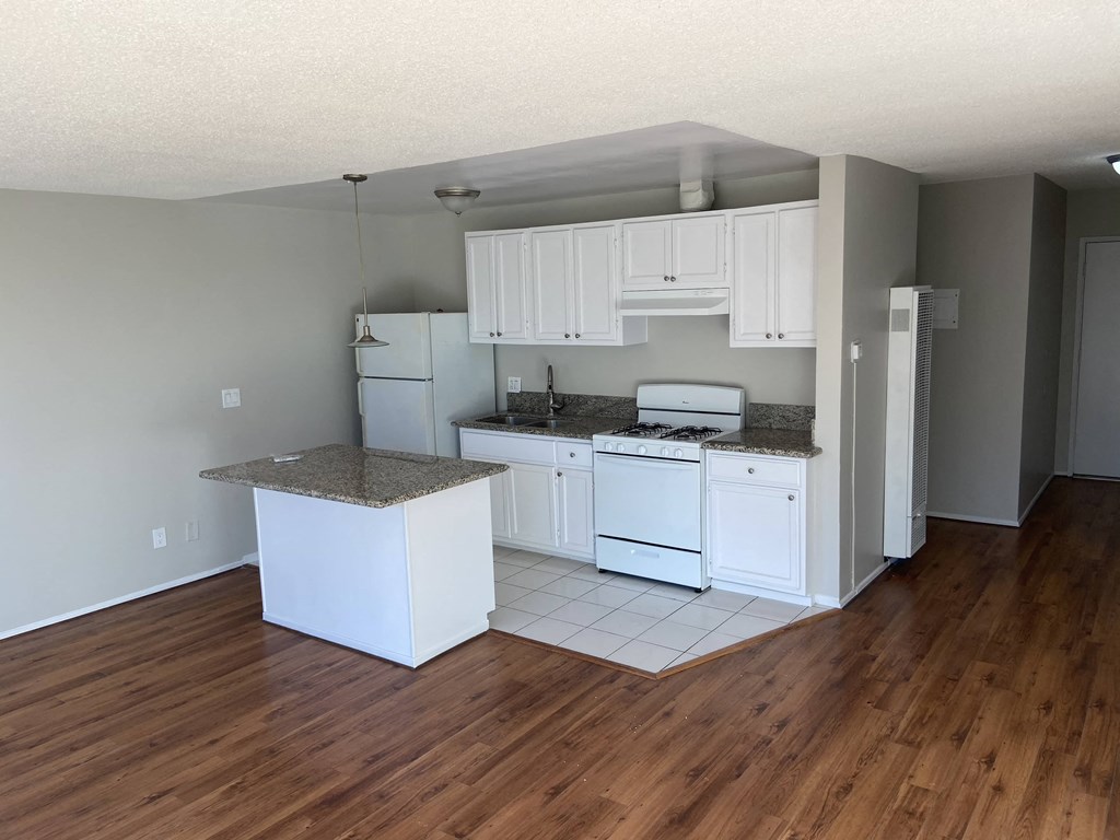a kitchen with white cabinets and a wood floor