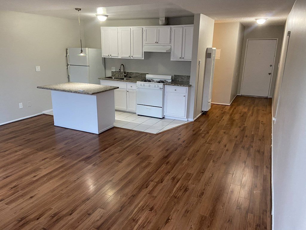 an open kitchen with white cabinets and a wooden floor