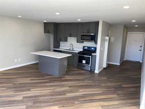 a renovated kitchen with a wooden floor and gray cabinets