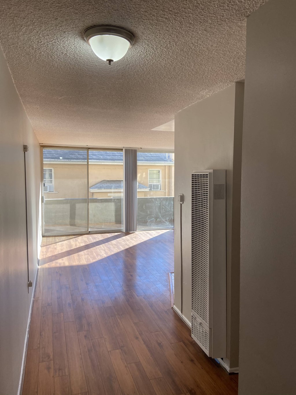 an empty living room with a window and a door to a balcony