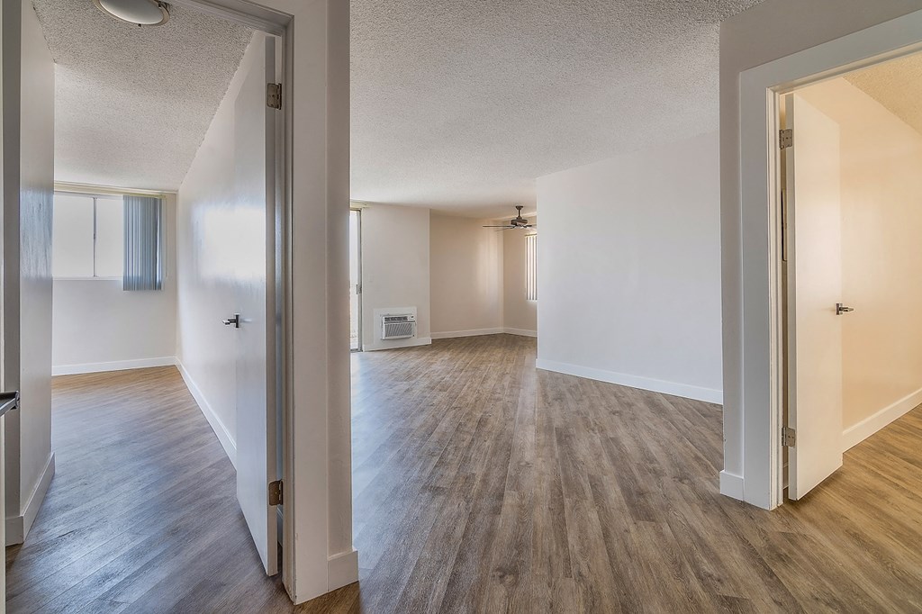 an open living room and dining room with wood flooring and white walls