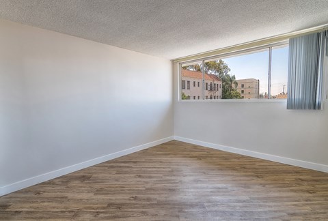 an empty living room with a large window and wood flooring