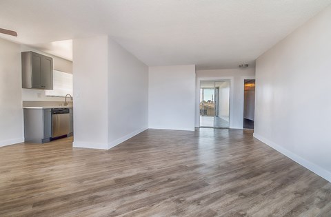 the living room and kitchen of an empty apartment with wood flooring