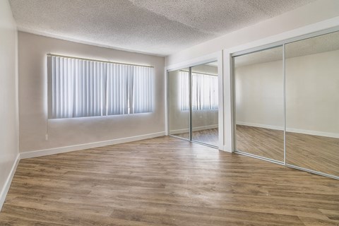 an empty living room with mirrored closet doors and a large window