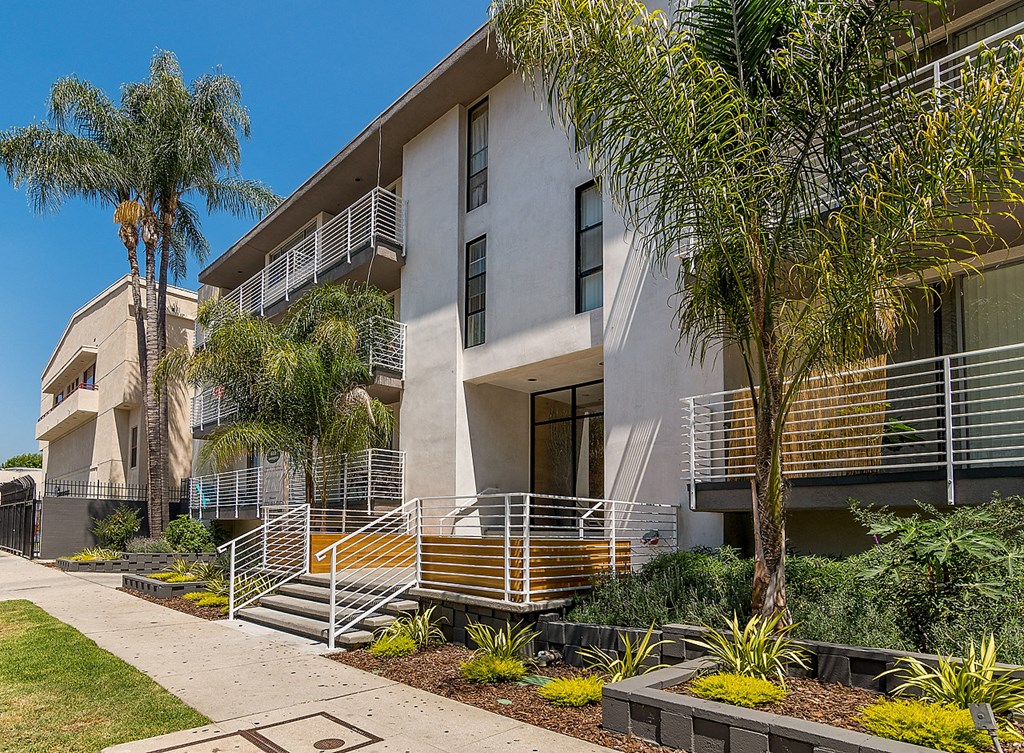 an apartment building with palm trees in front of it