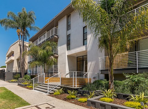 an apartment building with palm trees in front of it