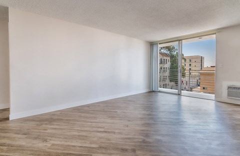 an empty living room with a sliding glass door to a balcony