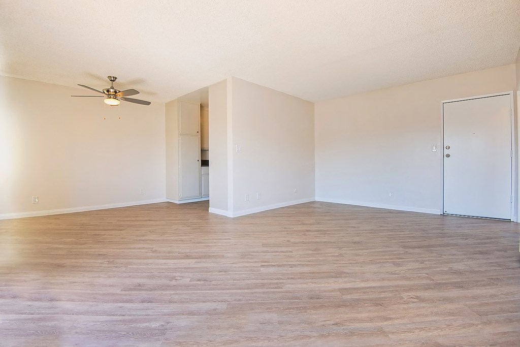 an empty living room with wood floors and a ceiling fan