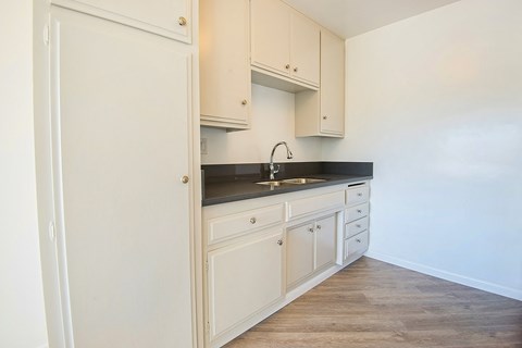 an empty kitchen with white cabinets and a sink