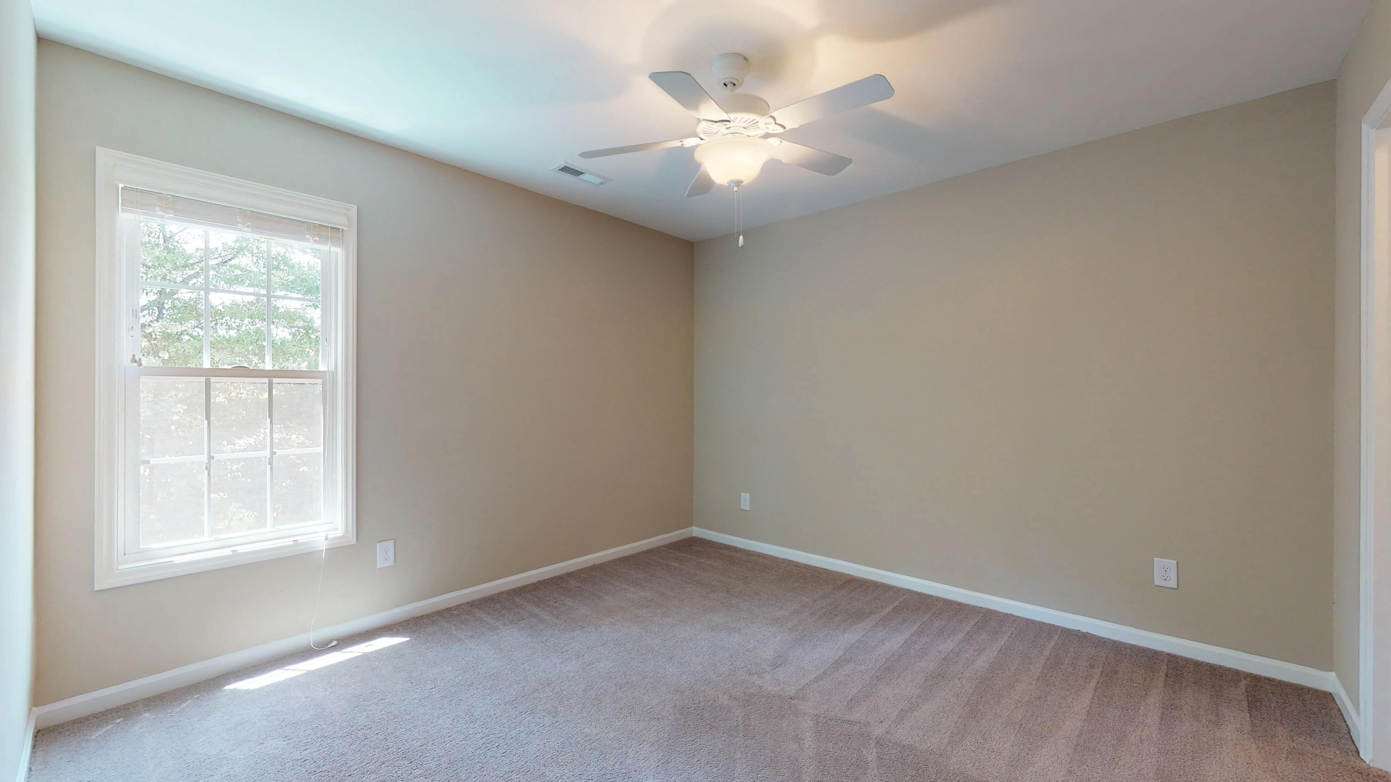 an empty room with a ceiling fan and a window