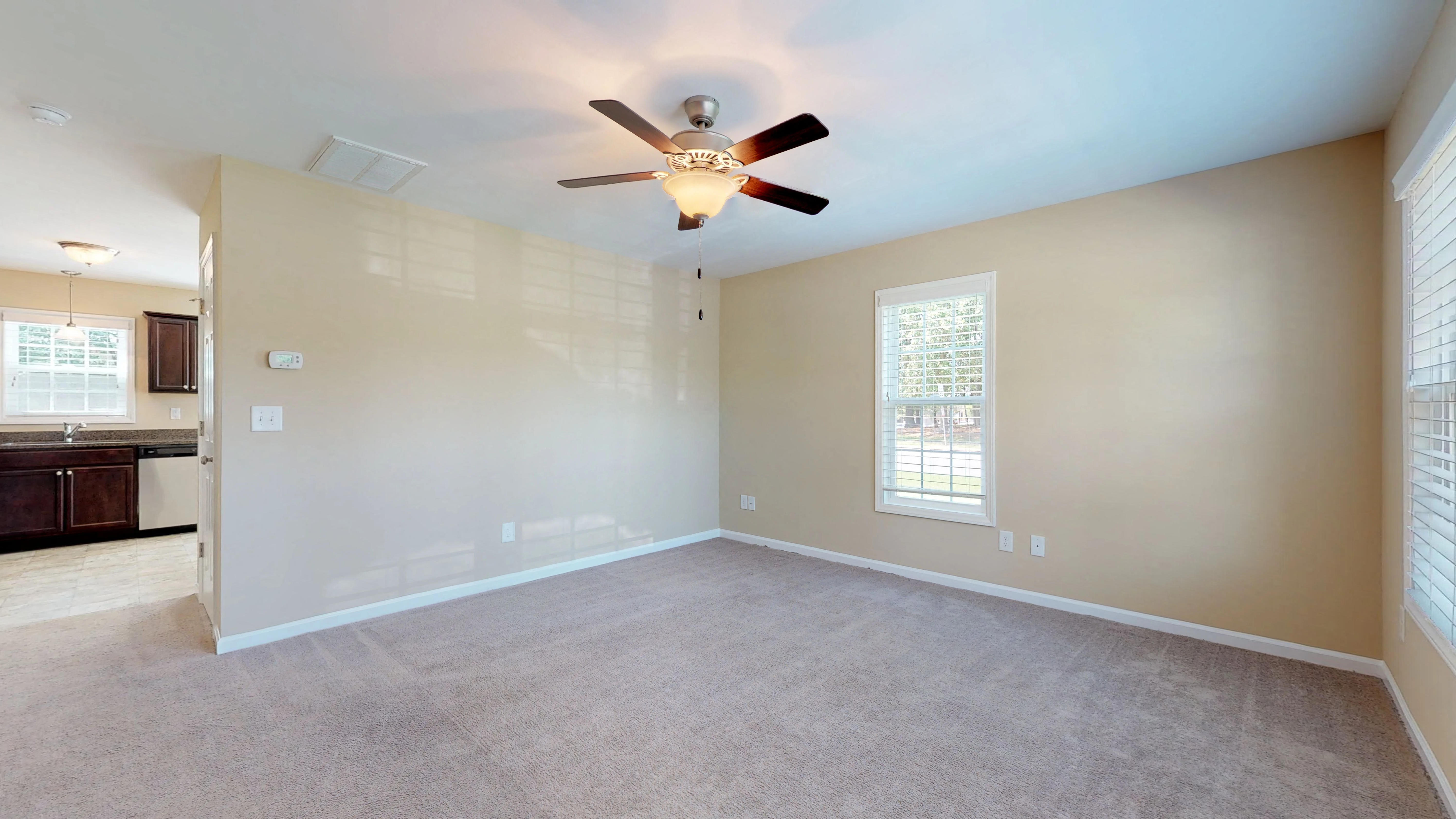 an empty living room with a ceiling fan