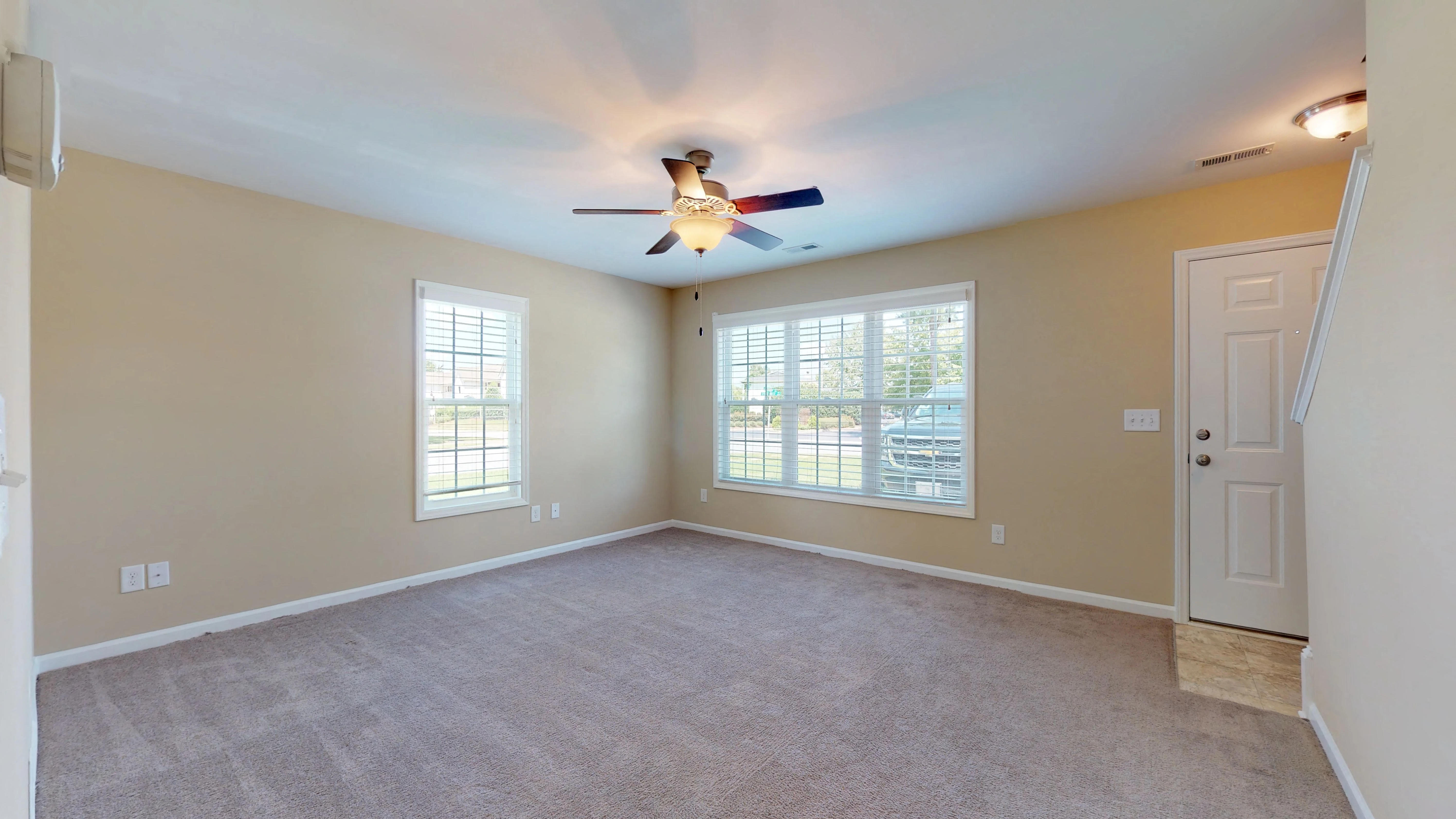 an empty living room with a ceiling fan