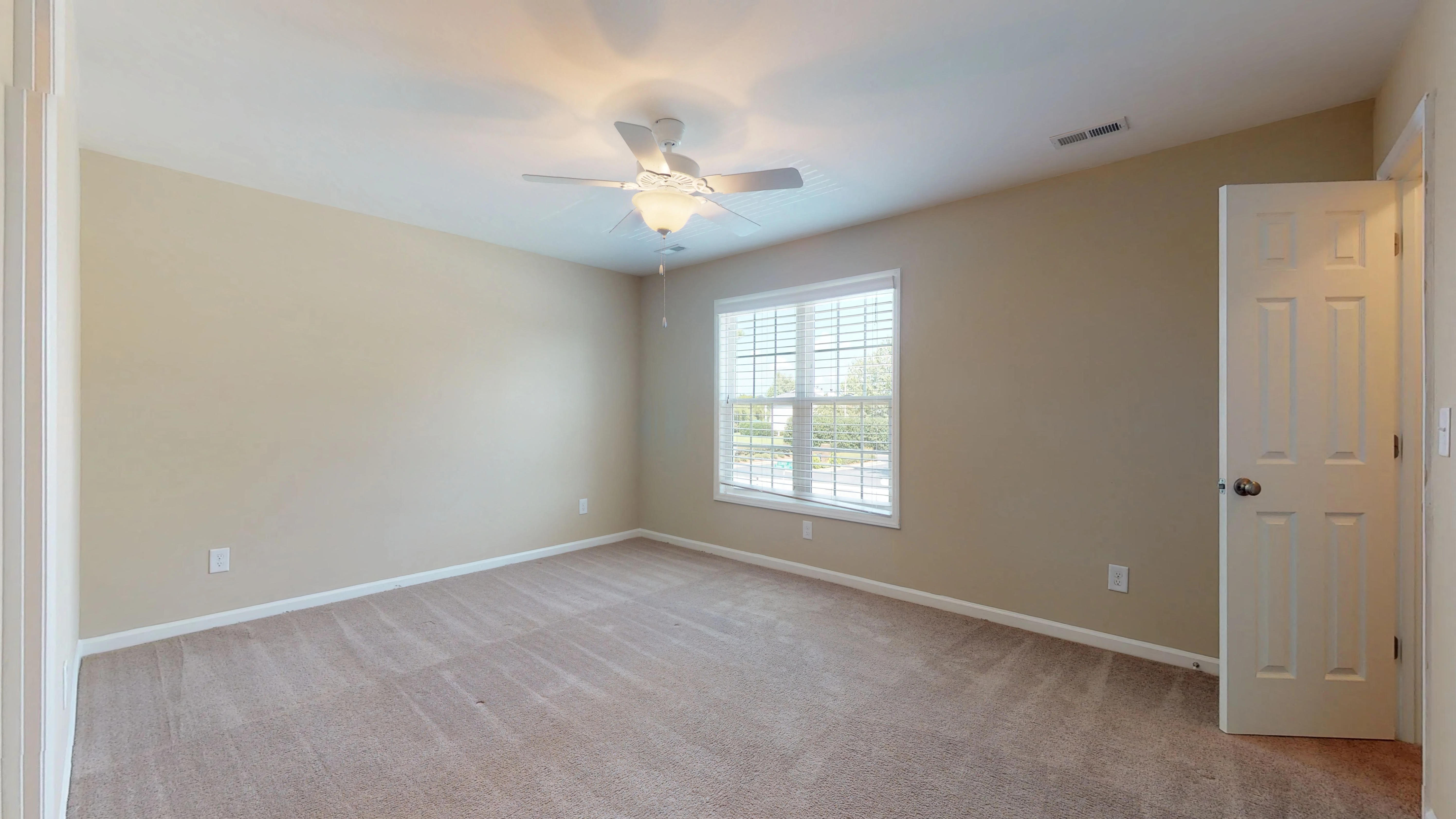 an empty living room with a ceiling fan and a window