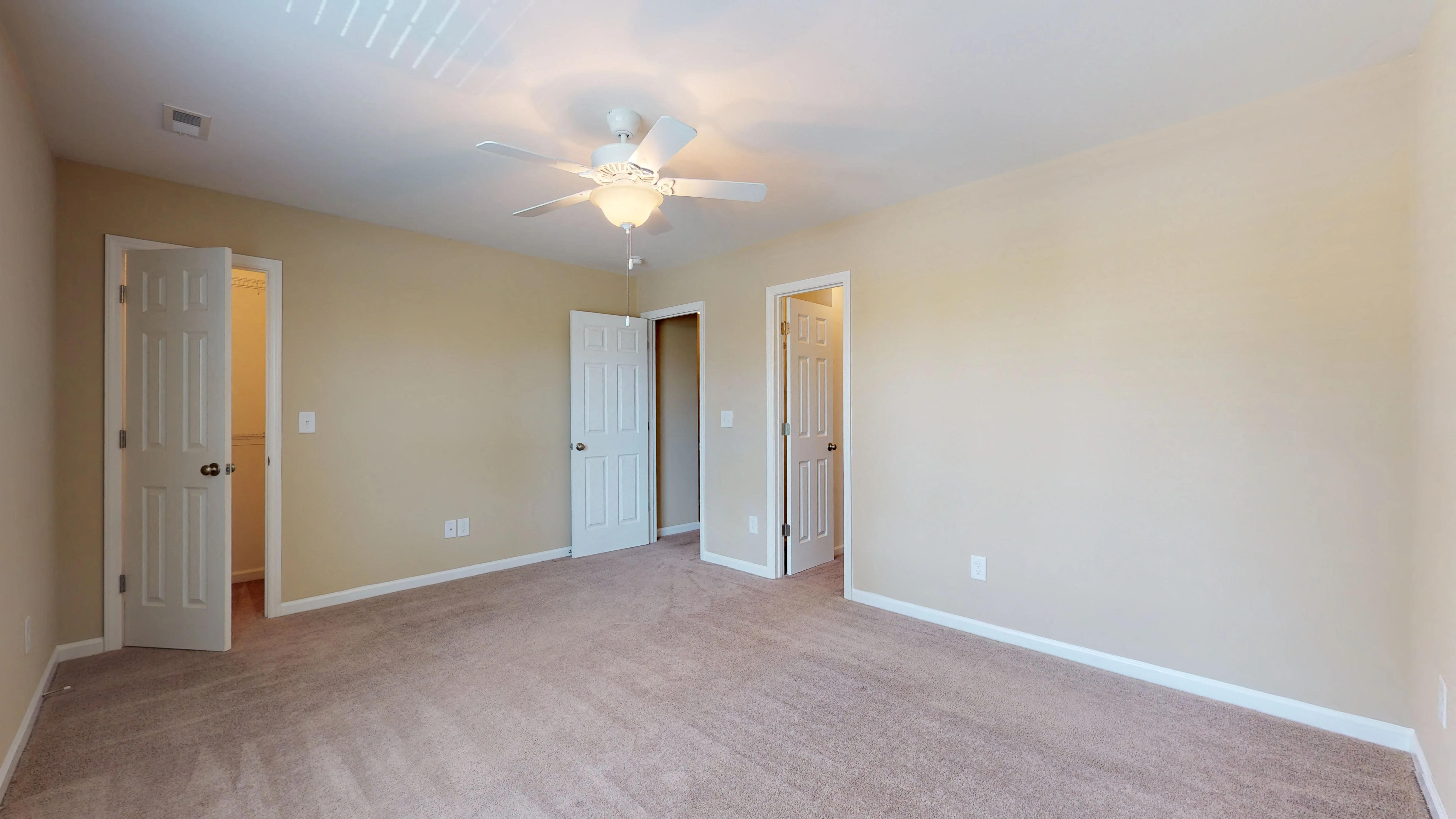 an empty living room with a ceiling fan and a carpet