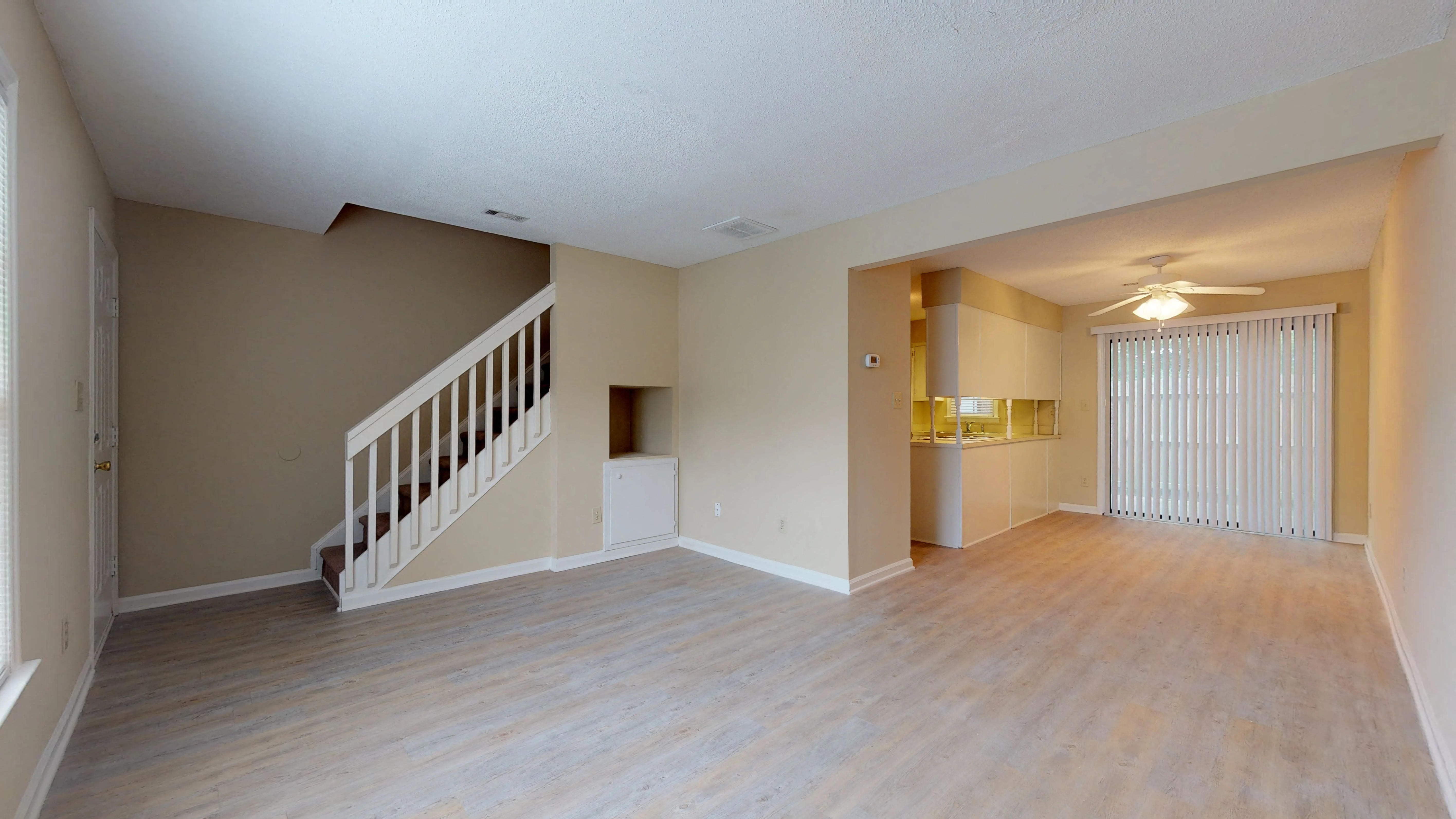 the living room and dining room of an empty house with a staircase