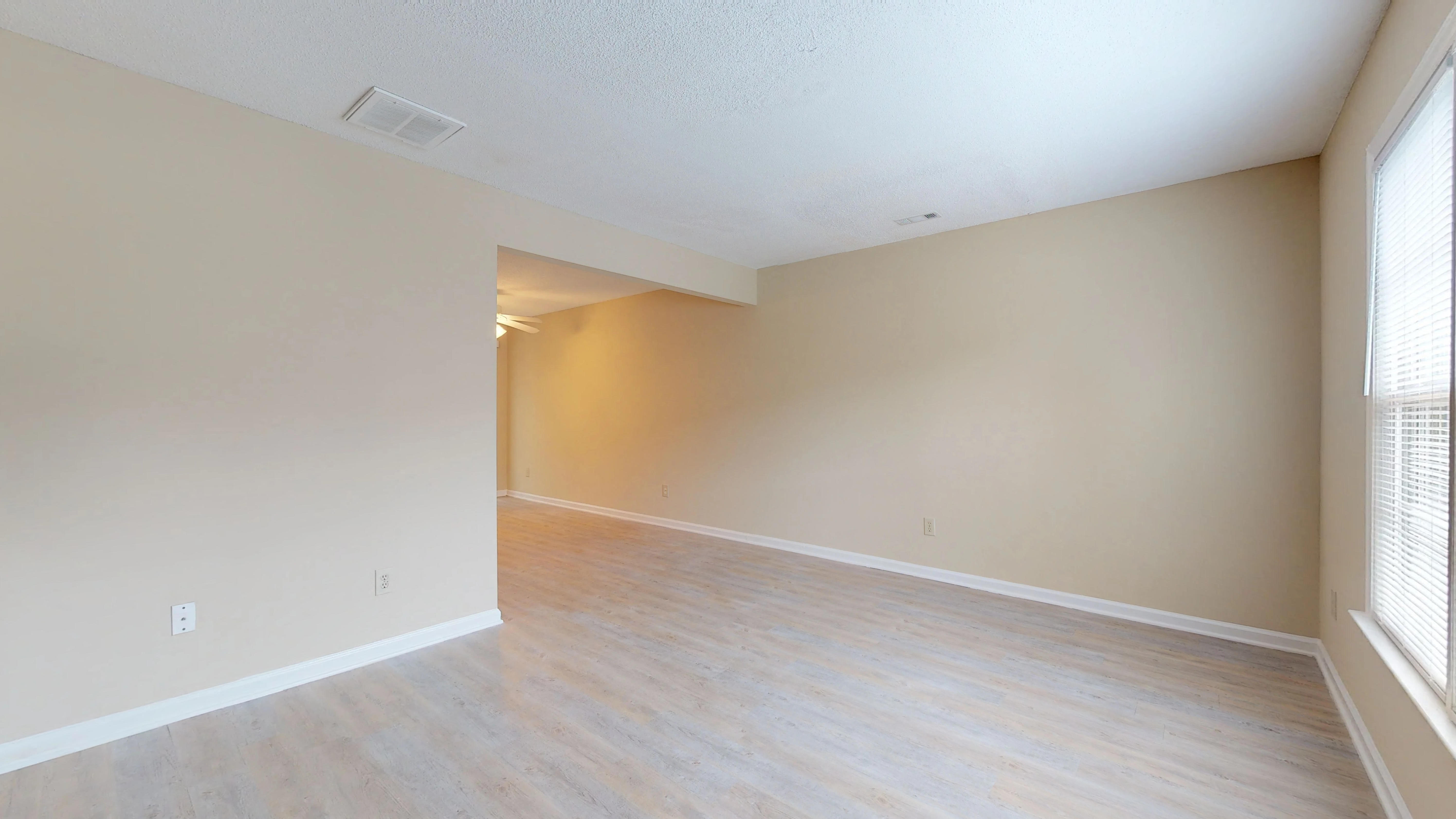 the living room and dining room of an empty home with wood flooring