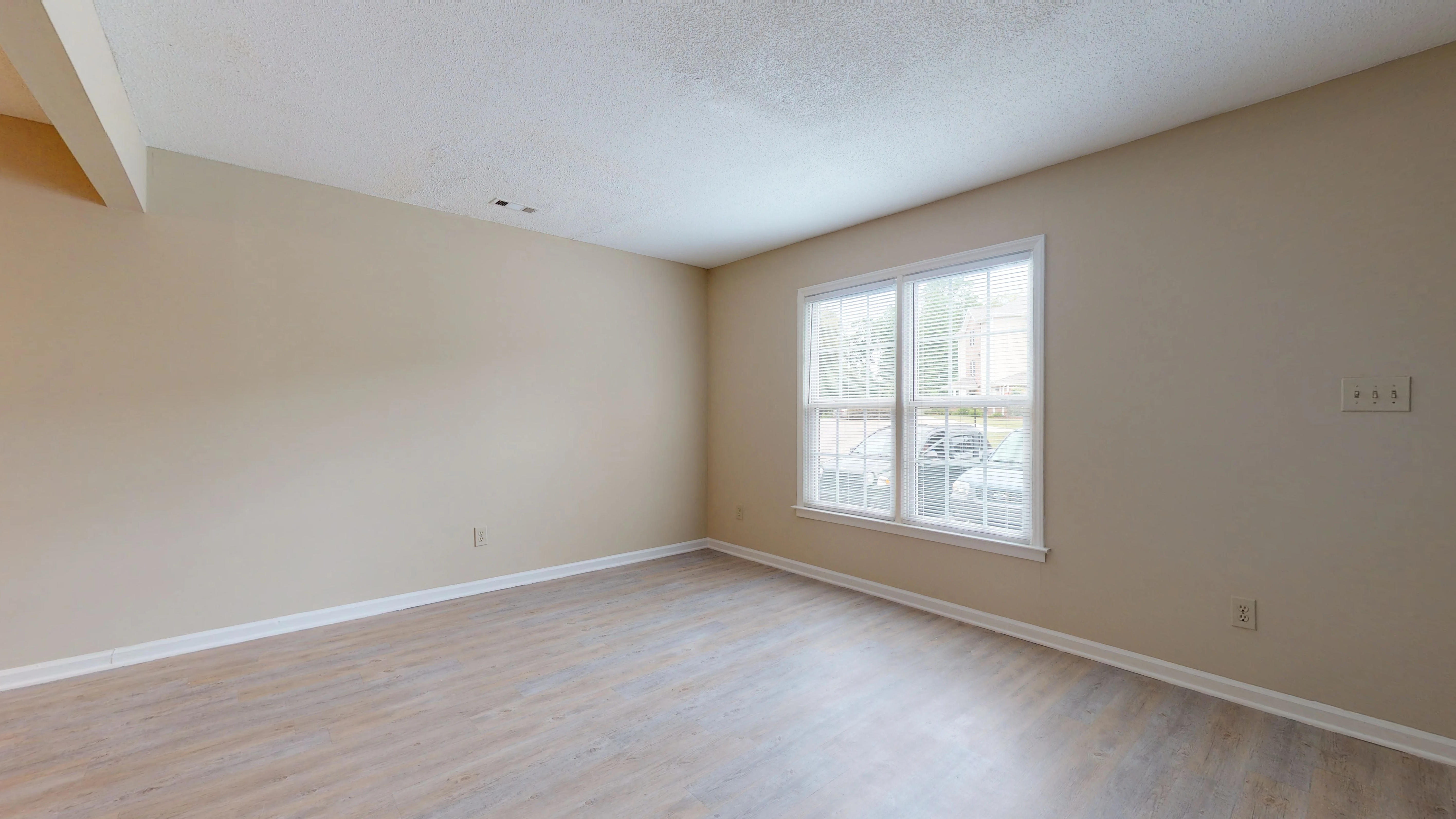 an empty living room with wood floors and a window
