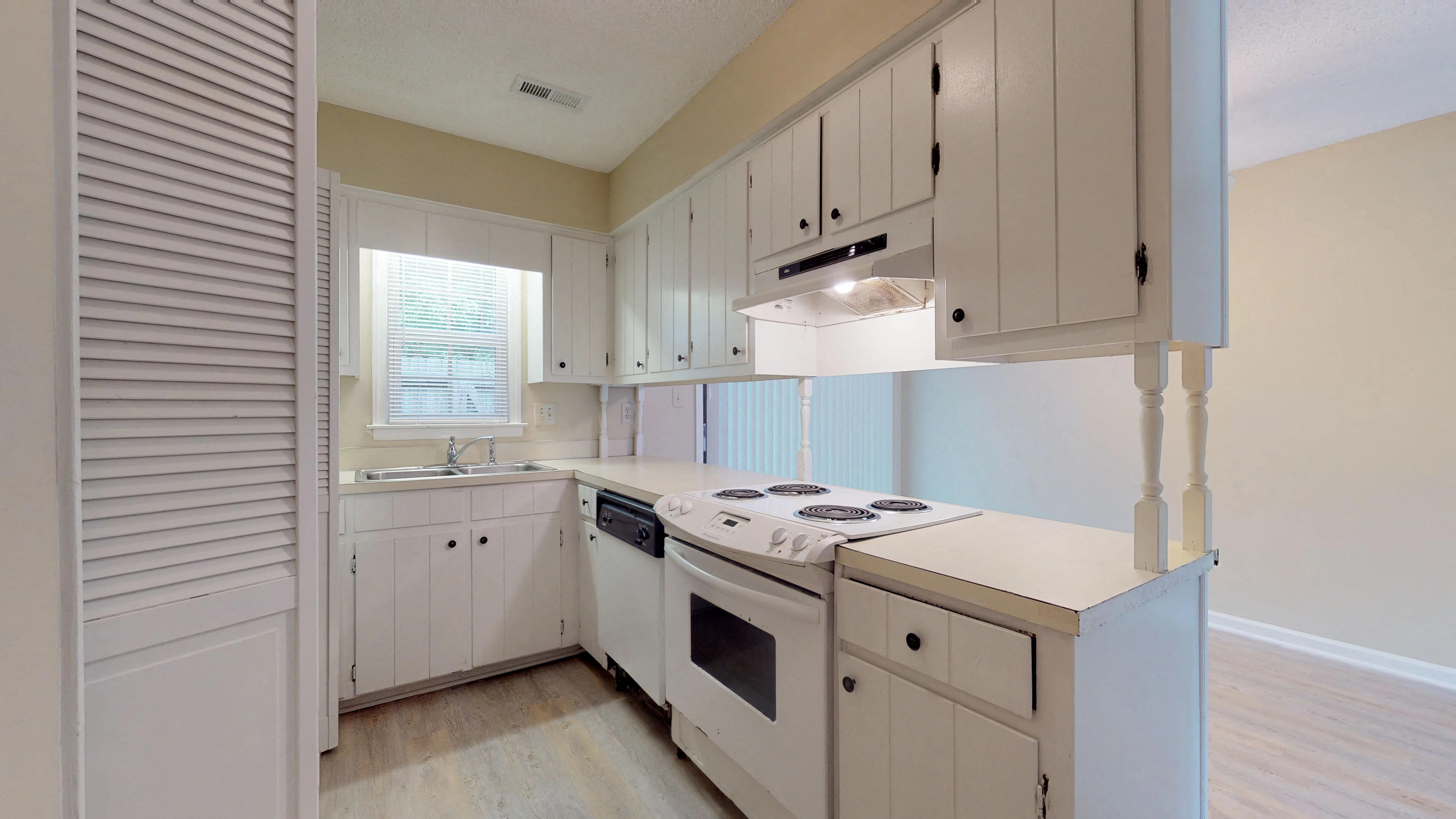 a white kitchen with white cabinets and a white stove