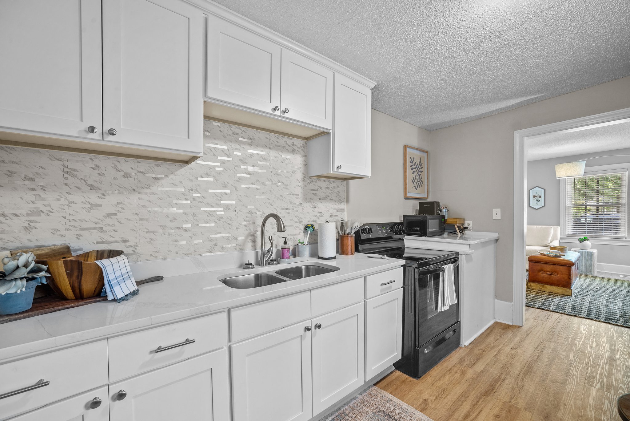 a kitchen with white cabinets and a black stove and sink
