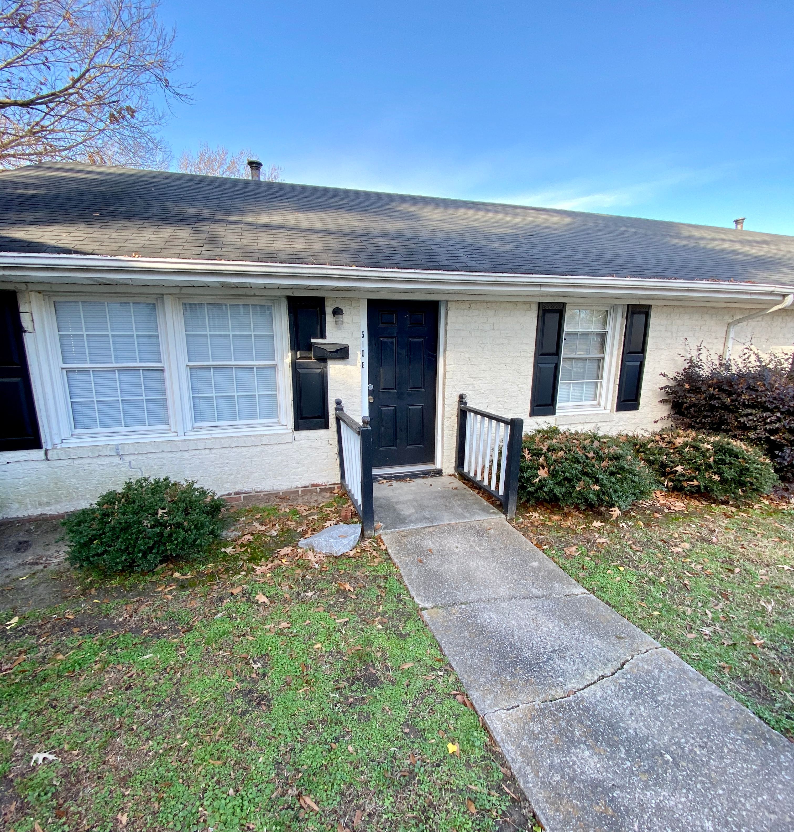 a small white house with a black door and a sidewalk