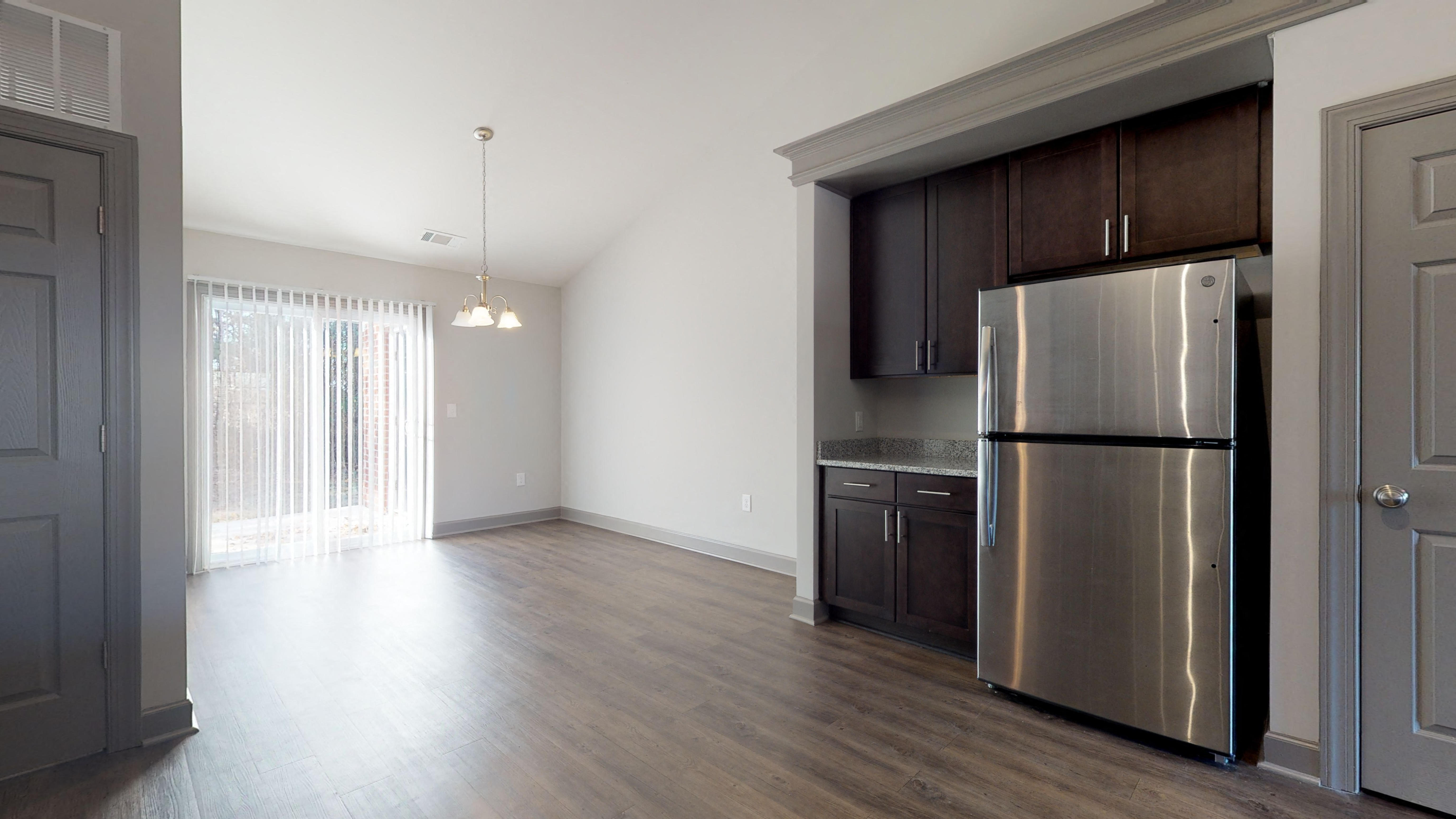an empty kitchen and living room with a stainless steel refrigerator