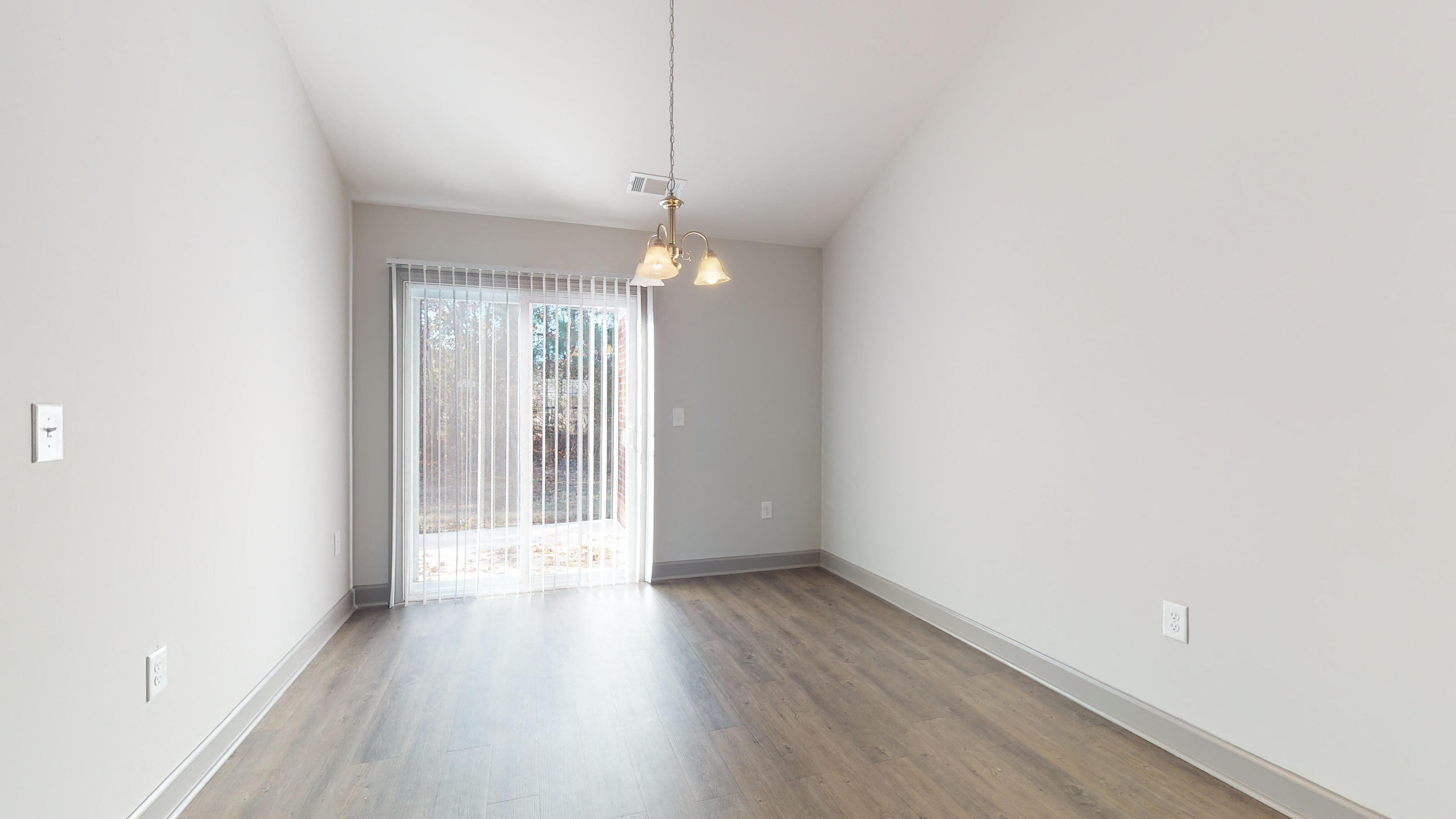 an empty living room with white walls and a sliding glass door