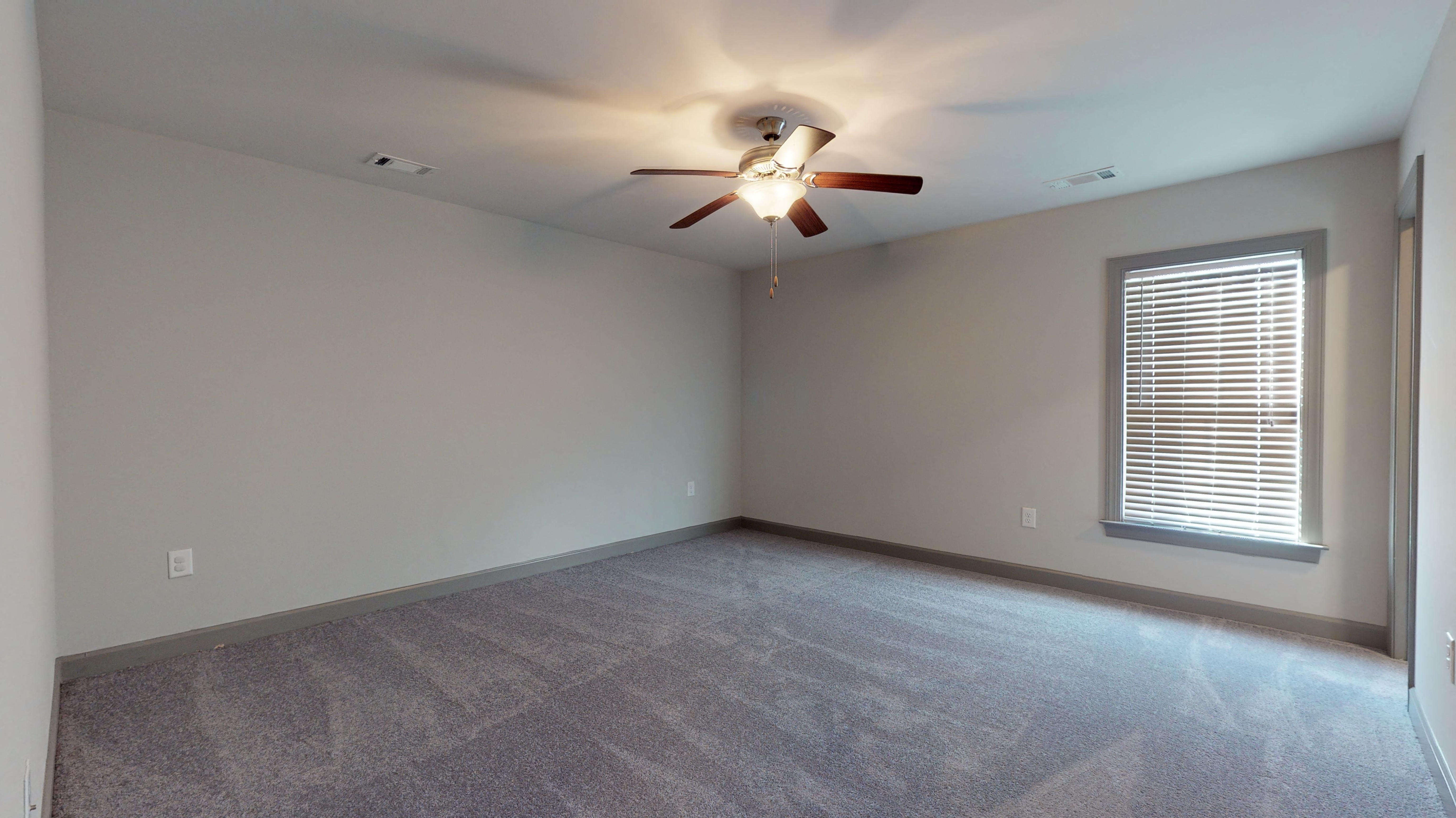 an empty living room with a ceiling fan and a window